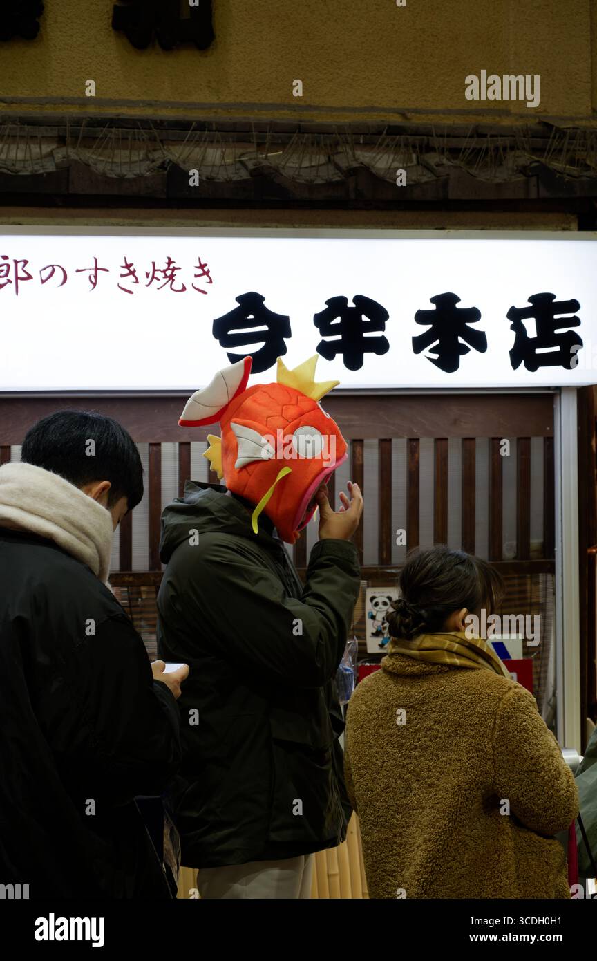 Mann mit verspieltem Magikarp-Hut, während er in einem Laden in Asakusa, Tokio, steht Stockfoto