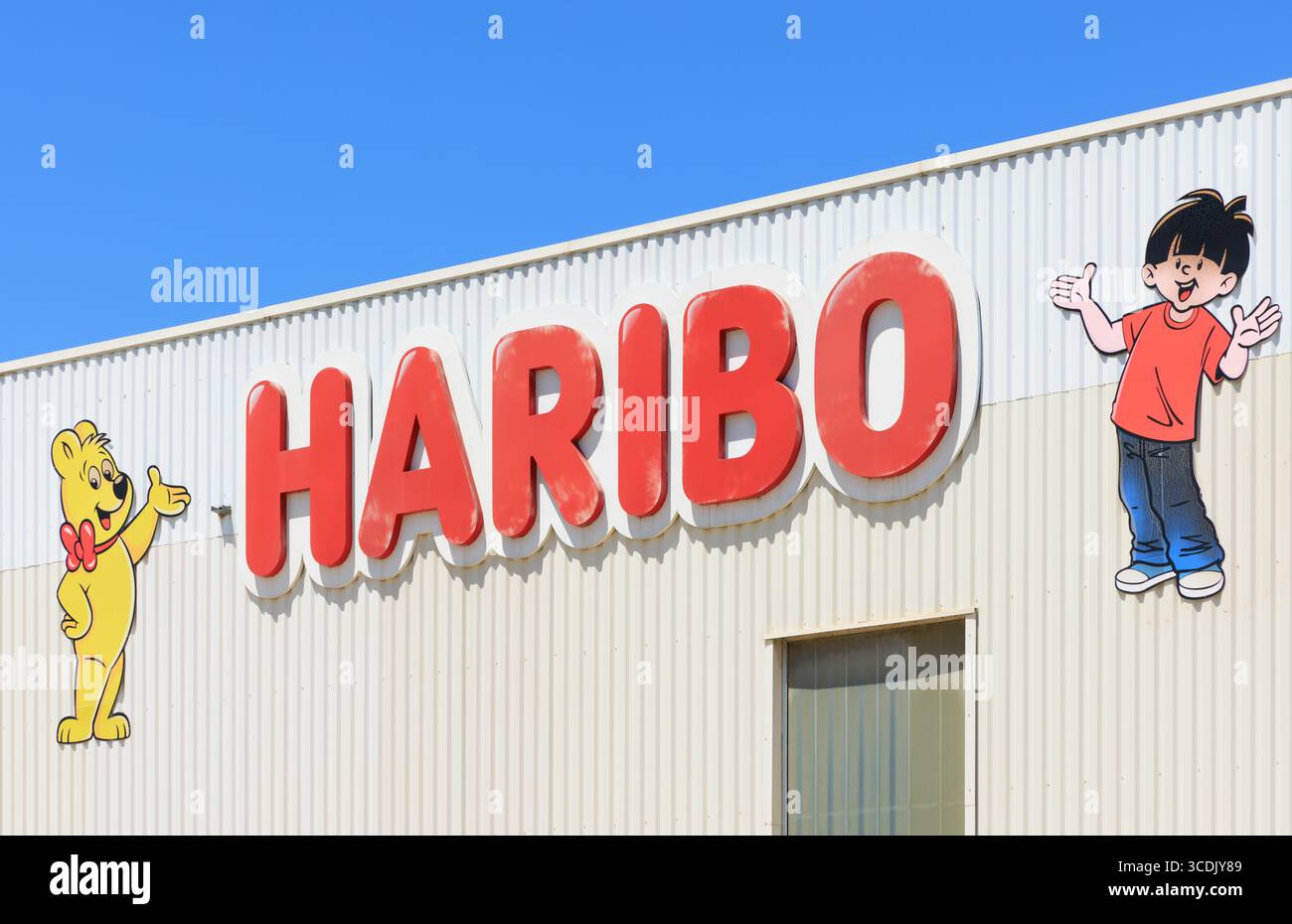 Haribo Süßwaren Zuckerfabrik Produktion mit auffälligem farbenfrohen Logo auf der Fassade einer Halle - Symbol und Konzept der Kindheit, Süßigkeiten und Trad Stockfoto