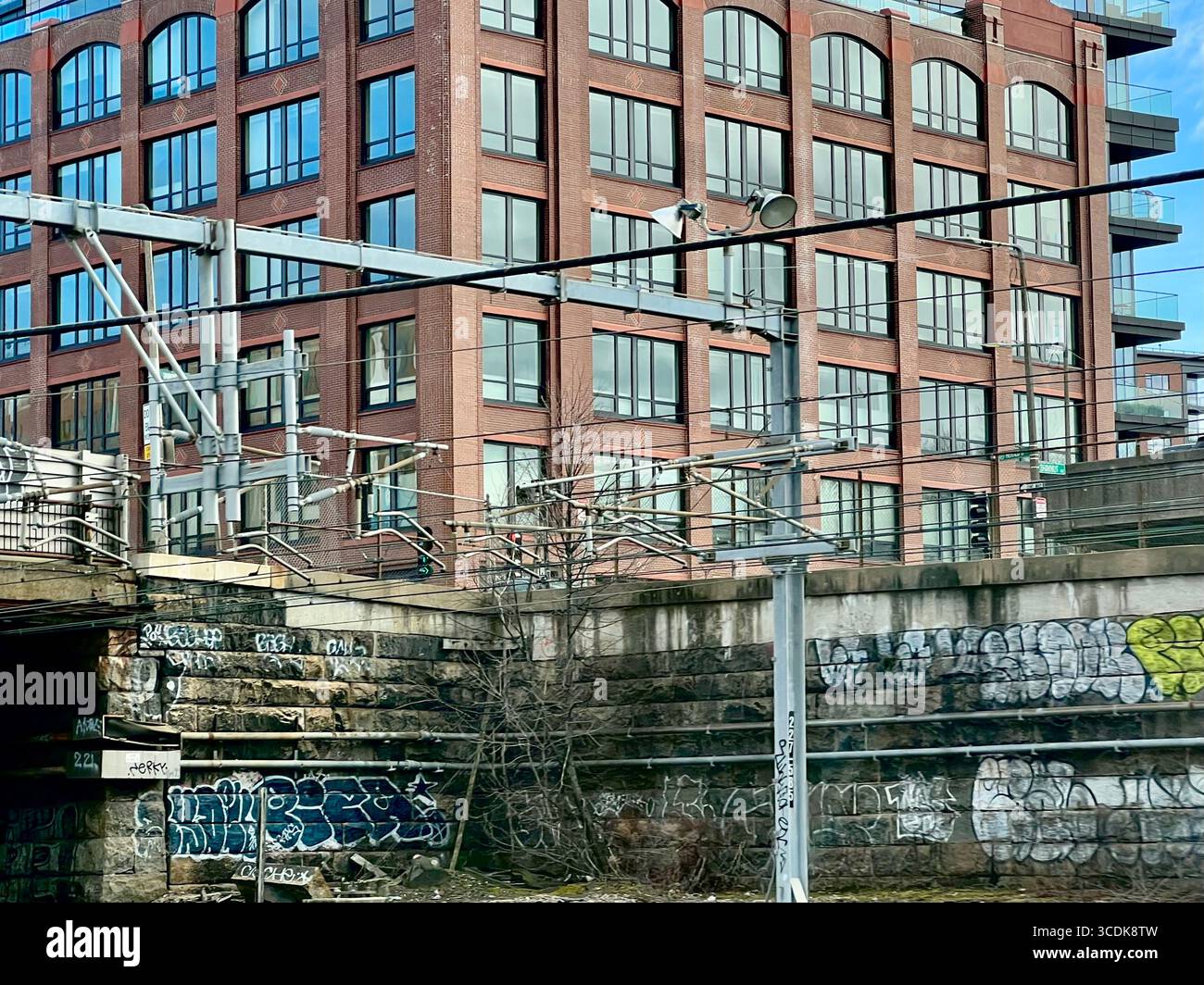 Graffiti an Steinmauern neben der Straße und dem roten Backsteingebäude in Boston. - Smartphone-aufgenommenes Stockfoto