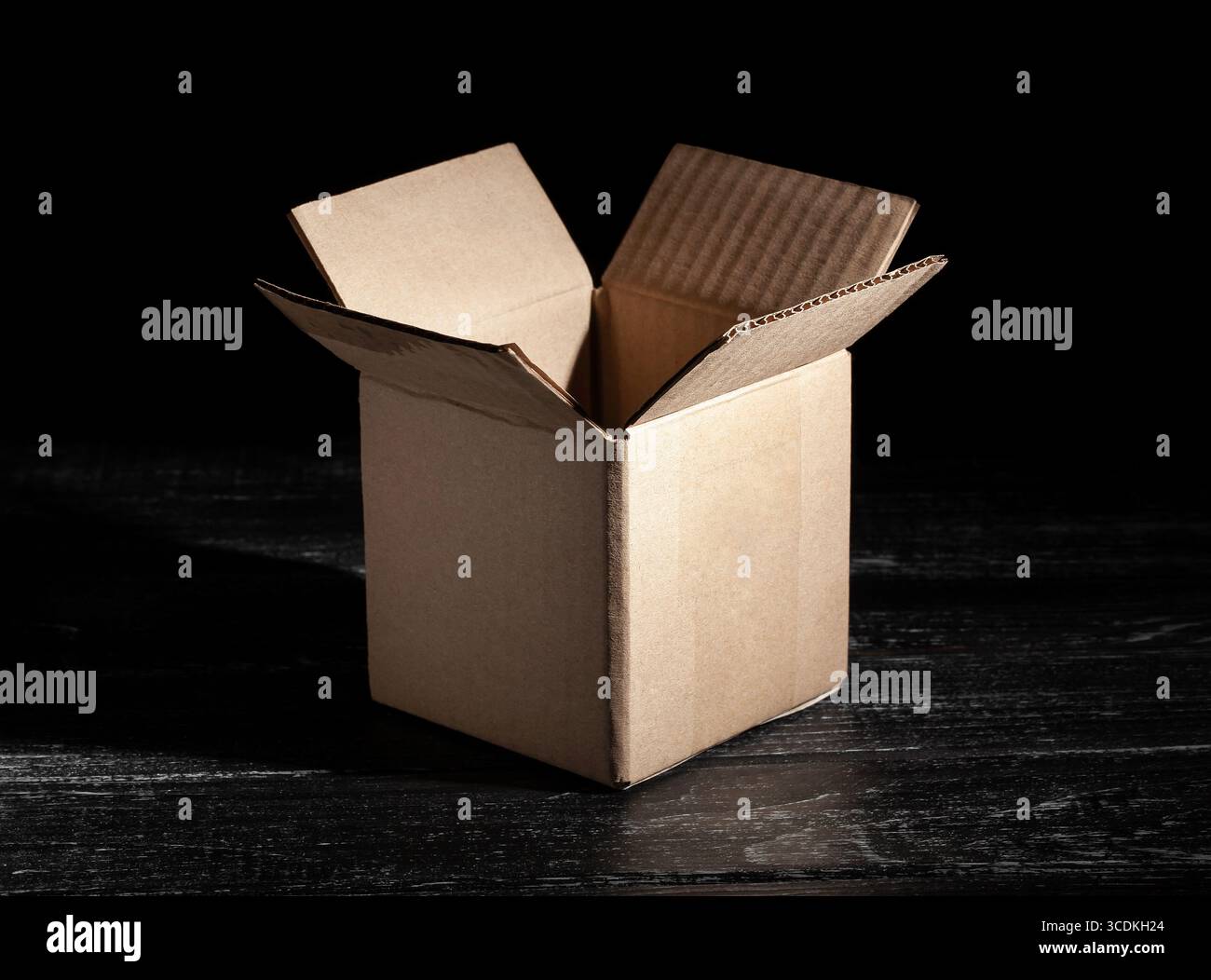 Öffnen Sie den Karton auf schwarzem Holzhintergrund Stockfoto