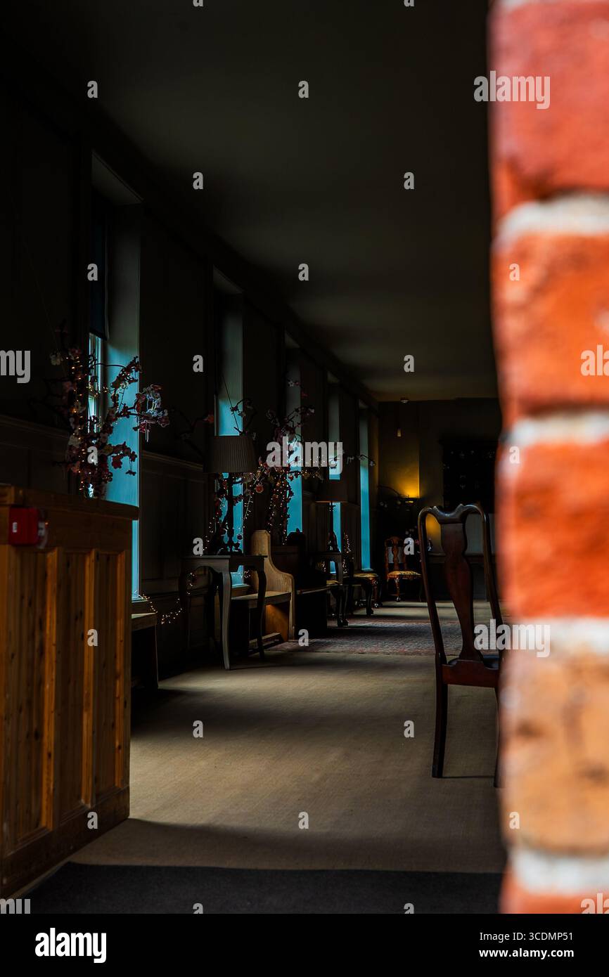 Gemütliches, schwach beleuchtetes Zimmer mit Vintage-Stühlen und blau getönten Fenstern Stockfoto