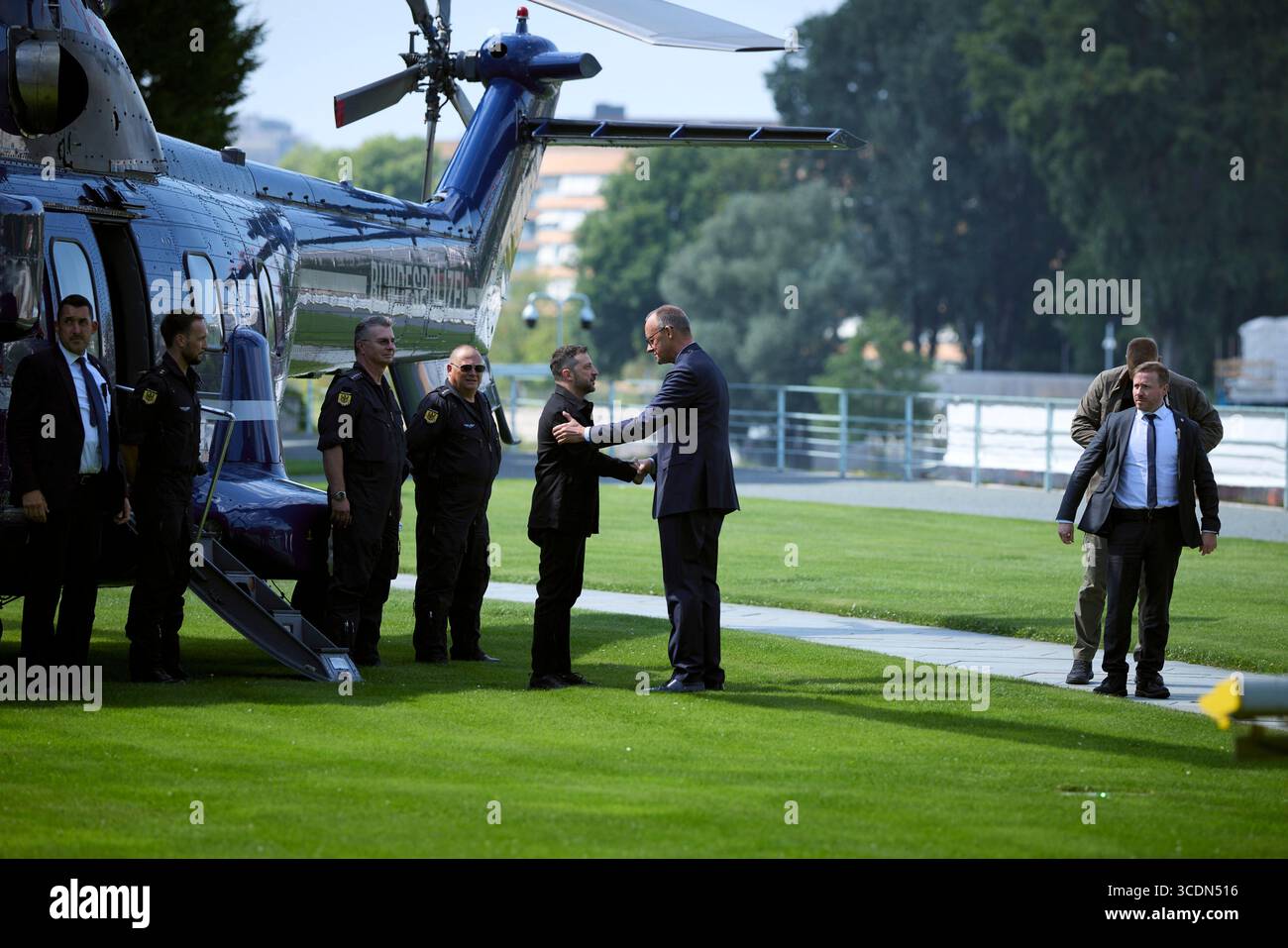 Berlin, Deutschland. August 2025. Der ukrainische Präsident Wolodymyr Zelenskyj, Zentrum, wird von Bundeskanzler Friedrich Merz, rechts, bei der Ankunft mit dem Hubschrauber im Kanzleramt am 13. August 2025 in Berlin begrüßt. Zelenskyy besucht ein virtuelles Gipfeltreffen mit europäischen Staats- und Regierungschefs und US-Präsident Donald Trump. Quelle: Pool Photo/Ukrainische Präsidentenpresse/Alamy Live News Stockfoto