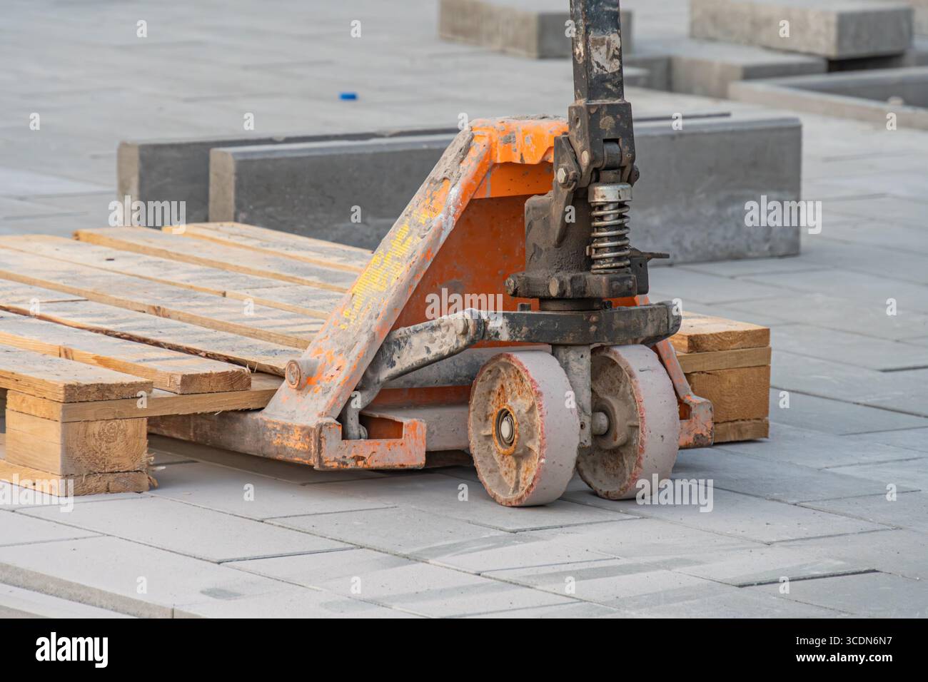 Industriegalettenhubwagen, der auf Holzpaletten oder -Kisten steht, was eine schwere Lagerung oder Logistik in einem industriellen Umfeld vorschlägt Stockfoto