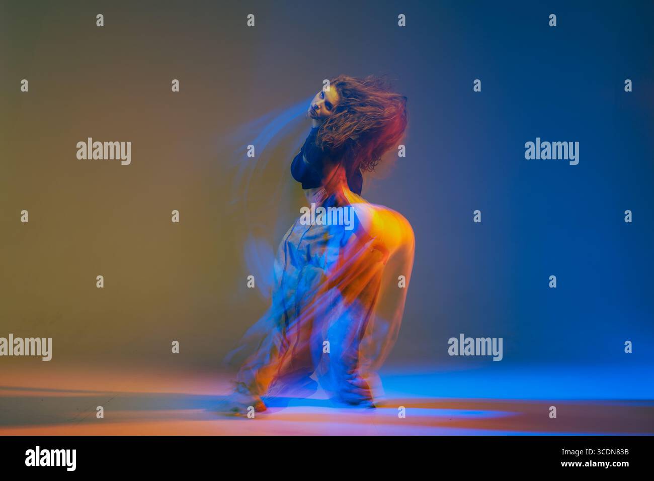 Ausdrucksstarke Jazz-Funk-Tänzerin in modernem Stil, die energiegeladene Choreografie mit lebendigen bunten Lichtern und dynamischen Bewegungen vorführt. Stockfoto