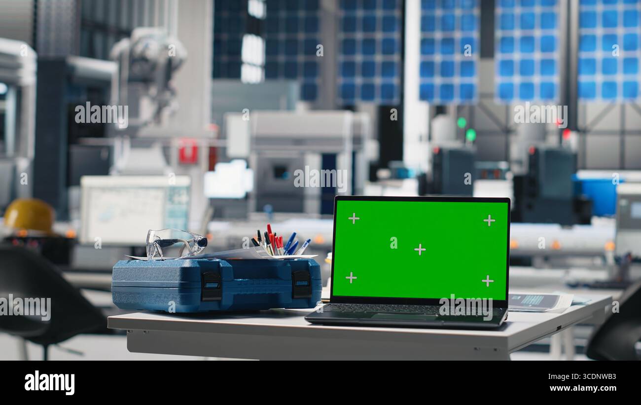 Grüner Bildschirm auf einem Laptop an einem leeren Photovoltaik-Schreibtisch zur Unterstützung der grünen Energie, die zur Optimierung der Energieversorgung in Solarpaneelen verwendet wird. High-Tech-Ingenieurindustrie. Stockfoto
