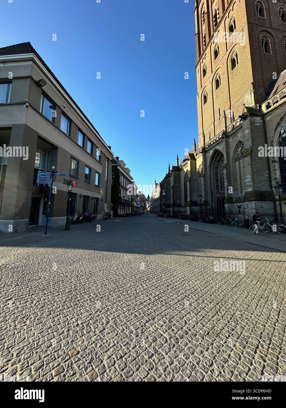 Kopfsteinpflasterstraße und Sint-Janskathedraal in ’s-Hertogenbosch, Niederlande, mit frühmorgendlichem Licht und historischer niederländischer Architektur. - Smartphone-aufgenommenes Stockfoto
