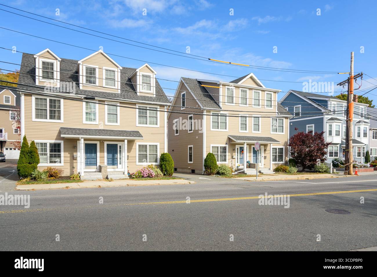 Reihe neuer Doppelhäuser entlang einer Straße in einer Vorstadtsiedlung an einem sonnigen Herbstmorgen Stockfoto
