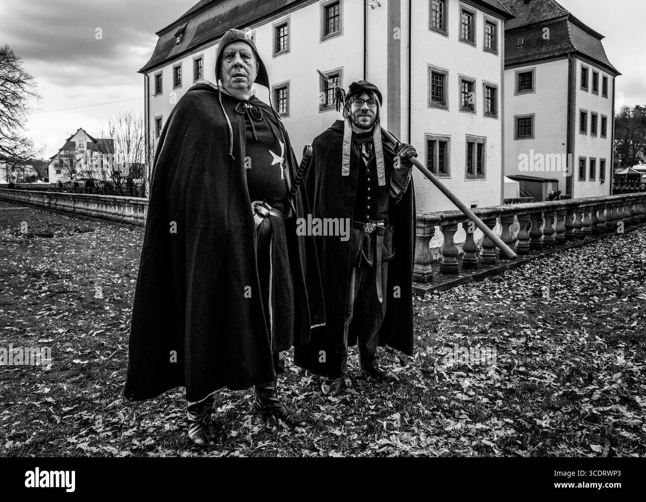 Zwei Männer in mittelalterlicher Kleidung posieren selbstbewusst vor einem historischen Gebäude Stockfoto