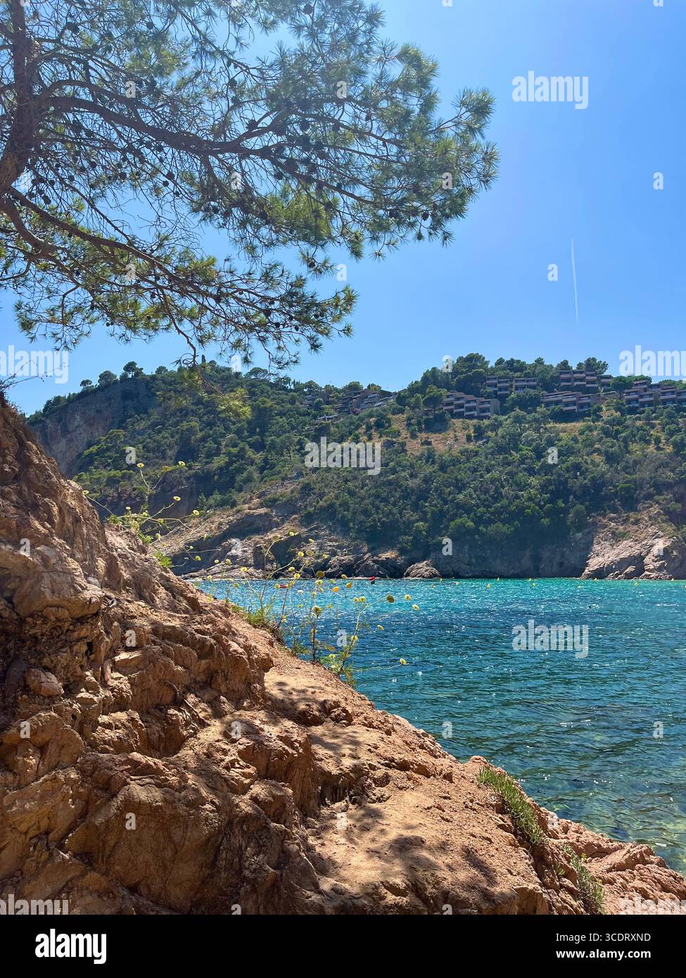 Spanische Küste mit kristallklarem blauem Wasser, Felsformationen und einem Berg im Hintergrund. - Smartphone-aufgenommenes Stockfoto