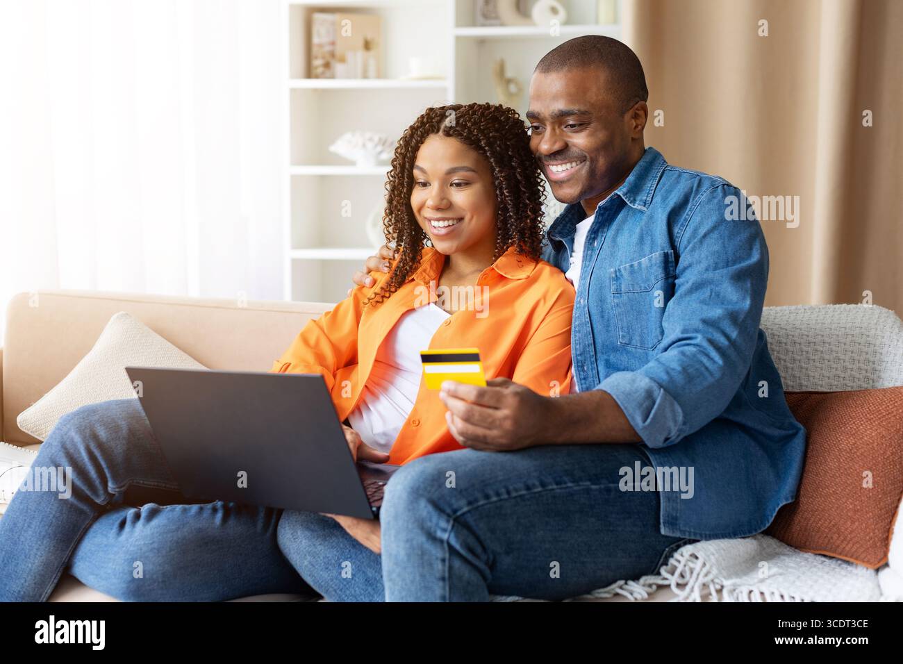 Schwarzes junges Paar online einkaufen mit Laptop und Kreditkarte zu Hause Stockfoto
