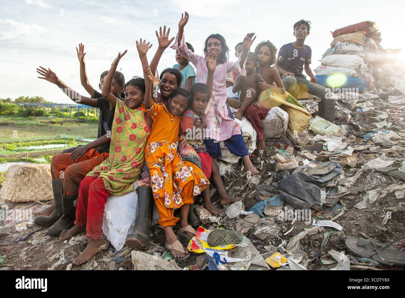 Chattogram, Bangladesch - 4. Oktober 2022: Blick auf eine Gruppe von Kindern, die sich fröhlich auf einem Müllhaufen hocken Stockfoto