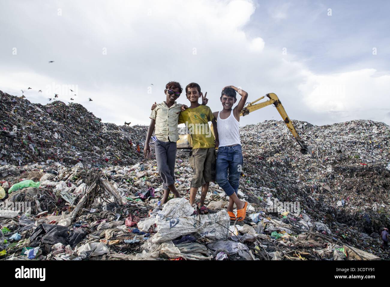 Chattogram, Bangladesch - 4. Oktober 2022: Blick auf drei lächelnde Jungen auf einem Berg von Abfall, ihre Jugendliche Freude ein krasser Kontrast zum umliegenden Verfall. Stockfoto