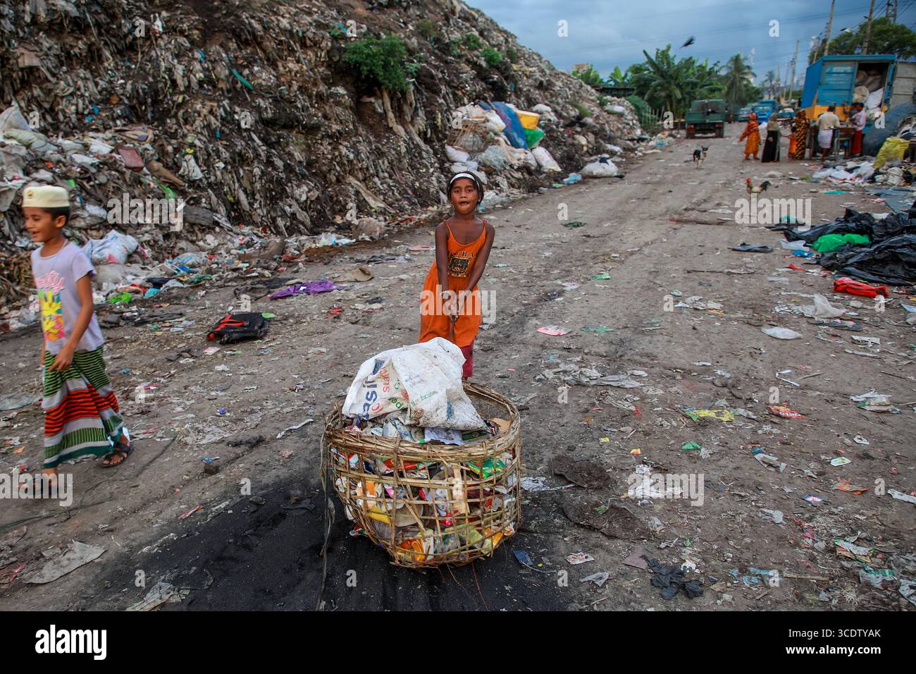 Chattogram, Bangladesch - 4. Oktober 2022: Blick auf Kinder inmitten der krasse Realität einer weitläufigen Mülldeponie, ihre helle Kleidung ein ergreifender Kontrast zu den gedämpften Tönen des Mülls. Stockfoto