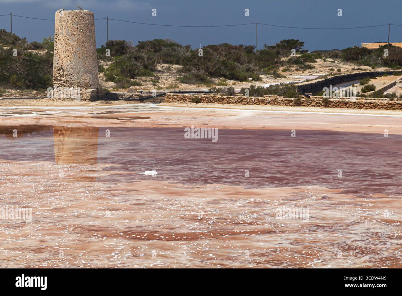 Salzteich und rustikaler Turm in Marroig Salt Flats, Formentera, Balearen, Spanien. Stockfoto