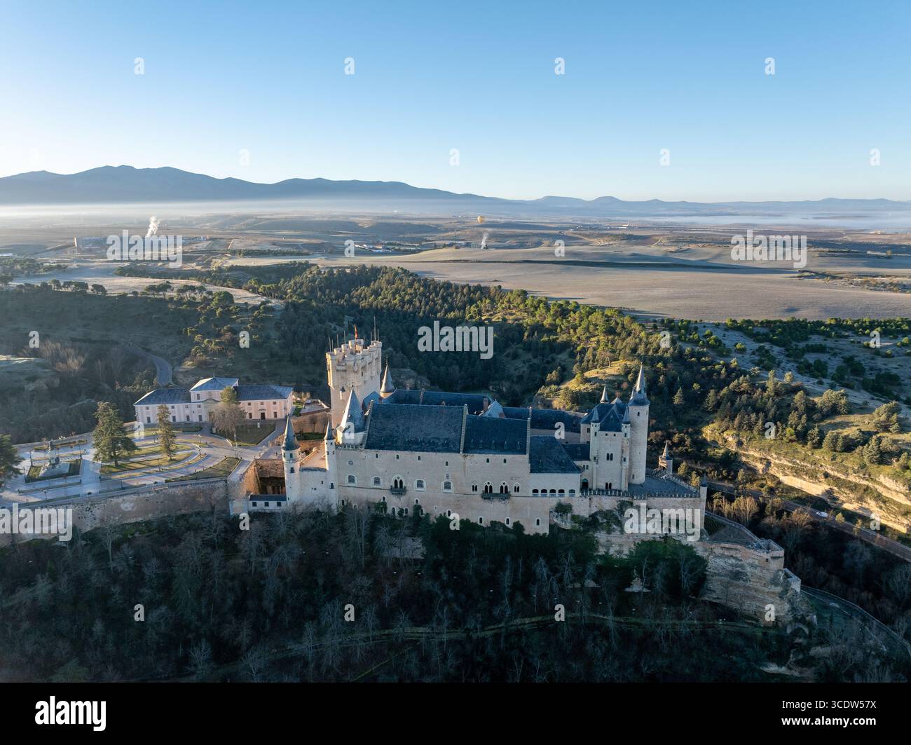 Blick aus der Vogelperspektive auf die Alcázar de Segovia, eine mittelalterliche Burg mit einzigartiger Silhouette, die auf einem felsigen Felsen thront, deren Steinmauern sanft im Mo leuchten Stockfoto