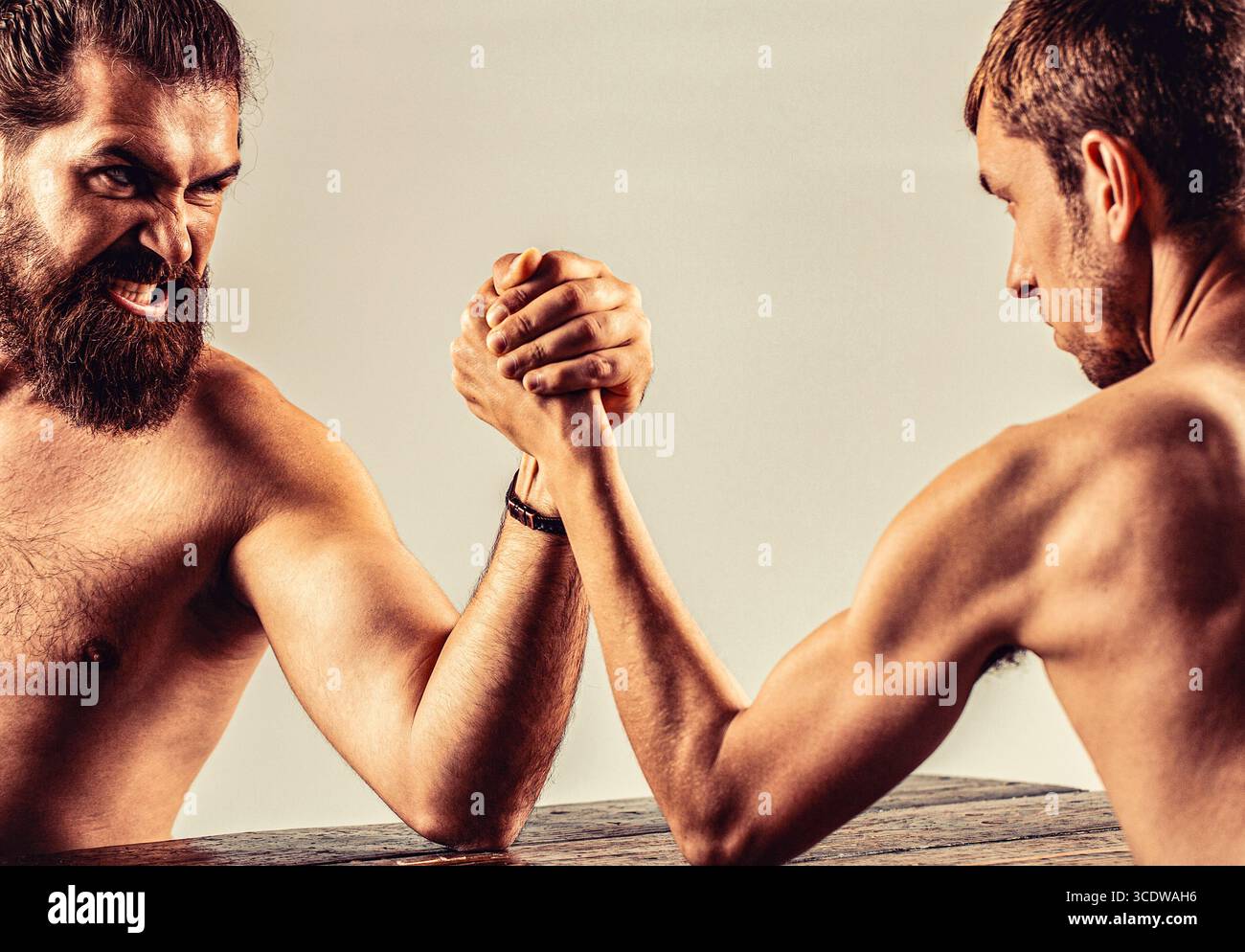 Armringen. Stark bemuskelter Mann Arm, der mit einem schwachen Mann kämpft. Arme mit dünner Hand, großer, starker Arm. Die Hände des Mannes verschlungen den Arm, stark Stockfoto
