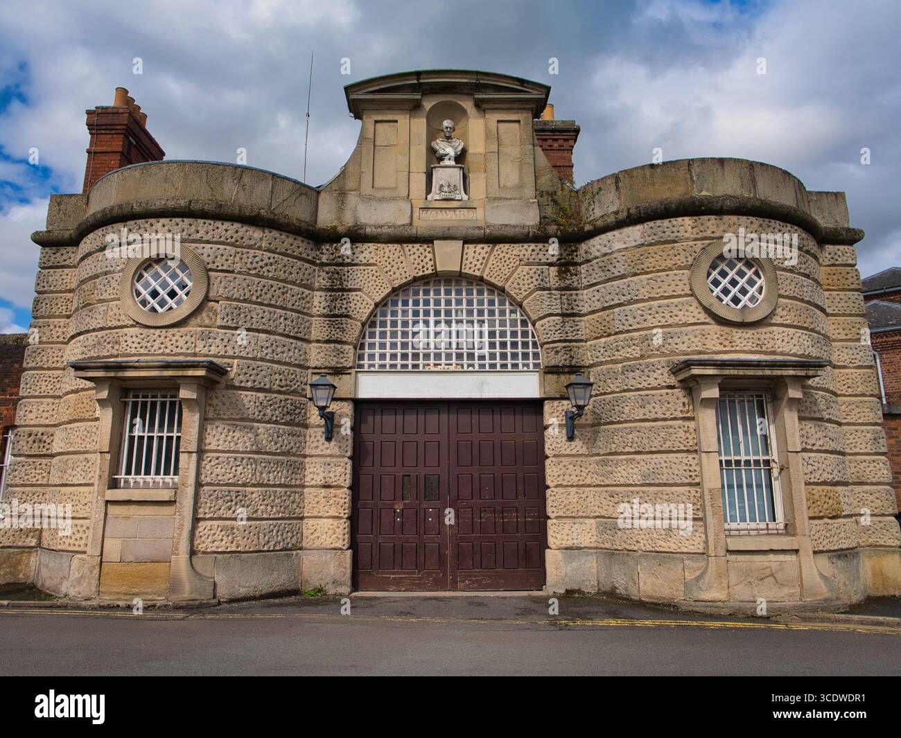 Shrewsbury, Großbritannien - 07. August 2025: Imposanter Steineingang des Shrewsbury Prison in Shrewsbury, Großbritannien, mit rustikalen Bögen, vergitterten Fenstern und einer zentralen Büste unter dramatischen Nachmittagswolken. Stockfoto