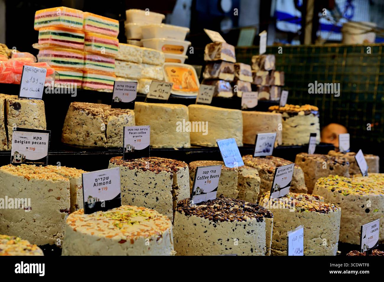 Stapel von Halva-Blöcken säumen einen Verkaufsstand am Carmel Market in Tel Aviv-Jaffa, Israel, mit einer farbenfrohen Ausstellung von Speisen aus dem Nahen Osten. Stockfoto