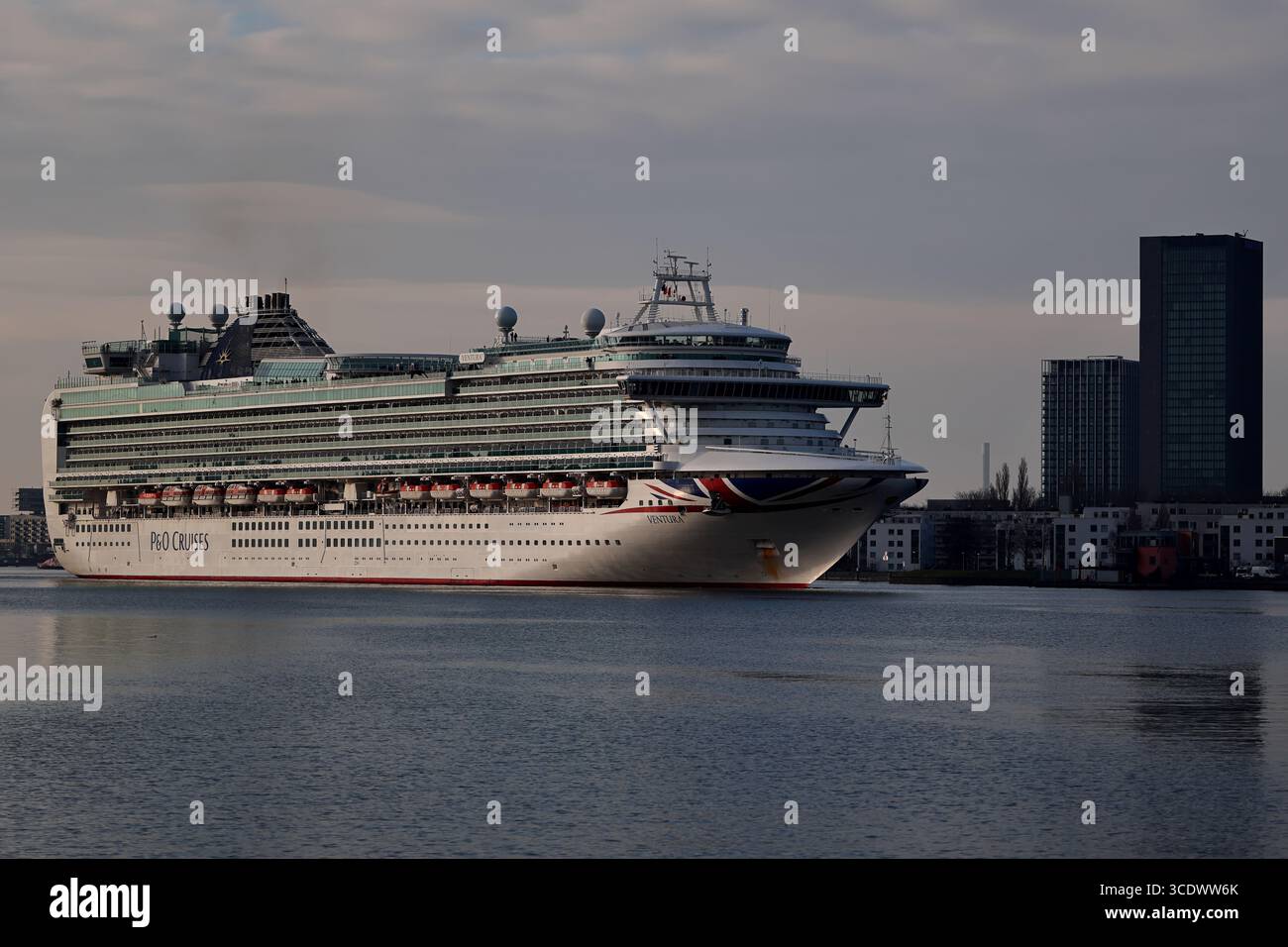 Kreuzfahrtschiff auf dem IJ mit City Skyline in Amsterdam, Niederlande, ruhige Hafenszene, geeignet für Reisen, redaktionelle und kommerzielle Lizenzen. Stockfoto