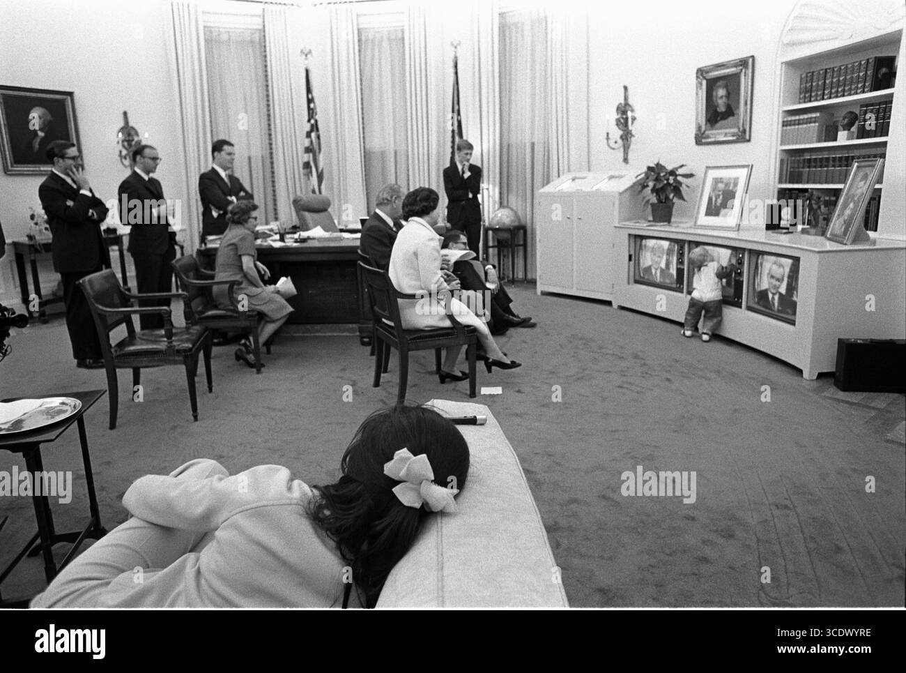 Lyndon B. Johnson 1968 im Weißen Haus - Präsident Lyndon B. Johnson, Familienmitglieder und Mitarbeiter beobachten die Ankündigung des Präsidenten, Bombenanschläge im Fernsehen zu stoppen Präsident Lyndon B. Johnson, Familienmitglieder und Mitarbeiter beobachten die Rede des Präsidenten auf drei Fernsehern. Enkel Patrick Lyndon Nugent, der sein Halloween-Kostüm trägt, spielt vor ihnen. Stockfoto