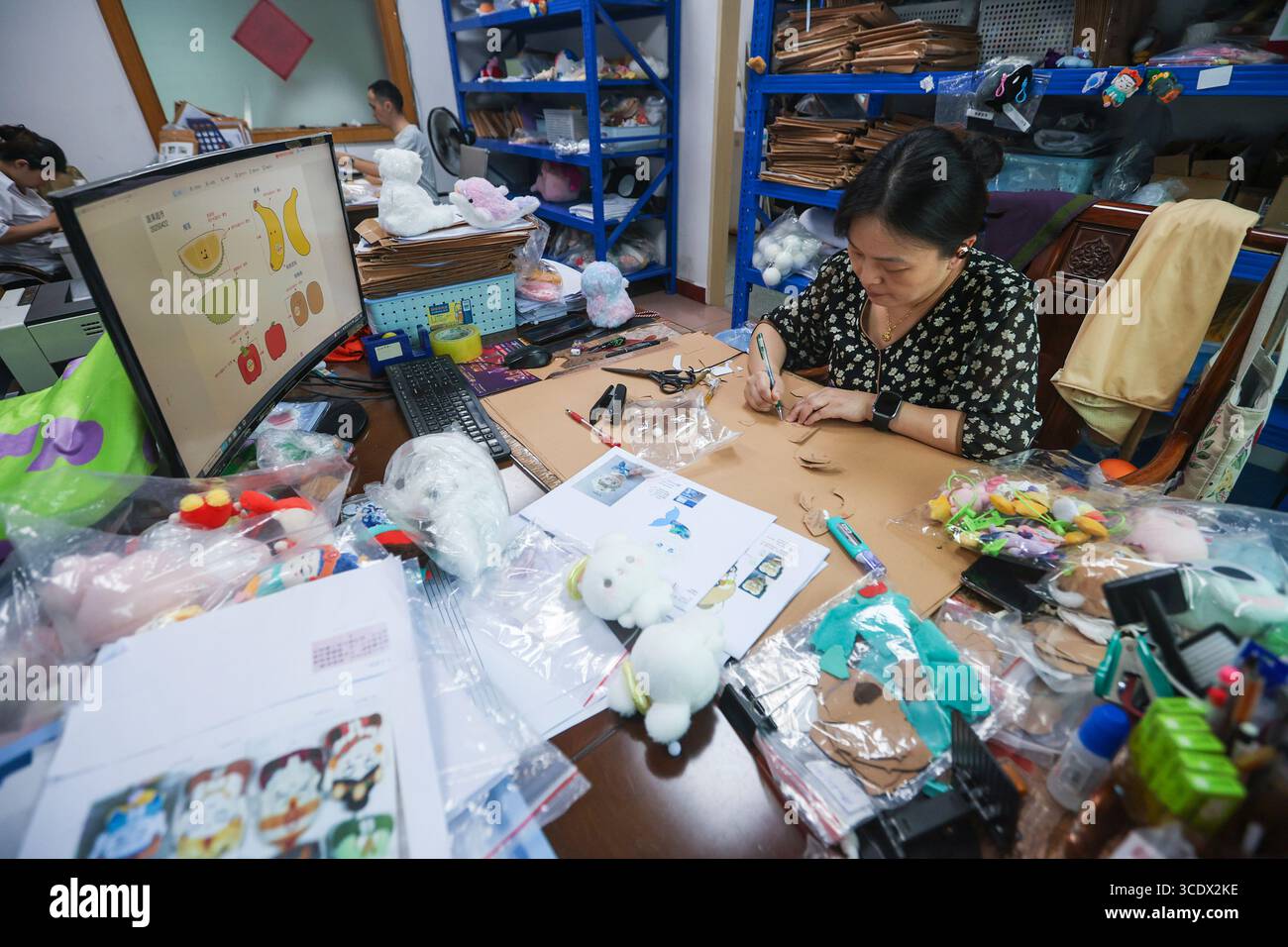 (250814) -- PEKING, 14. August 2025 (Xinhua) -- Ein Arbeiter schneidet Papiermuster aus, basierend auf Designzeichnungen in einer Spielzeugfabrik in Dongguan, südchinesischer Provinz Guangdong, 11. August 2025. In China haben in letzter Zeit immer beliebter werdende Taschen-Charms gewonnen, die es jungen Menschen ermöglichen, sich auszudrücken und gleichzeitig ein aufmunterndes Geschäft anzuheizen. Die Daten des E-Commerce aus dem diesjährigen Einkaufsbummel „18. Juni“ haben gezeigt, dass trendiges Spielzeug zu den stärksten Sektoren im „neuen Konsum“ des Landes zählt. Taschenanhänger haben sich zu einer vollwertigen Industriekette entwickelt, die von Original-des reicht Stockfoto