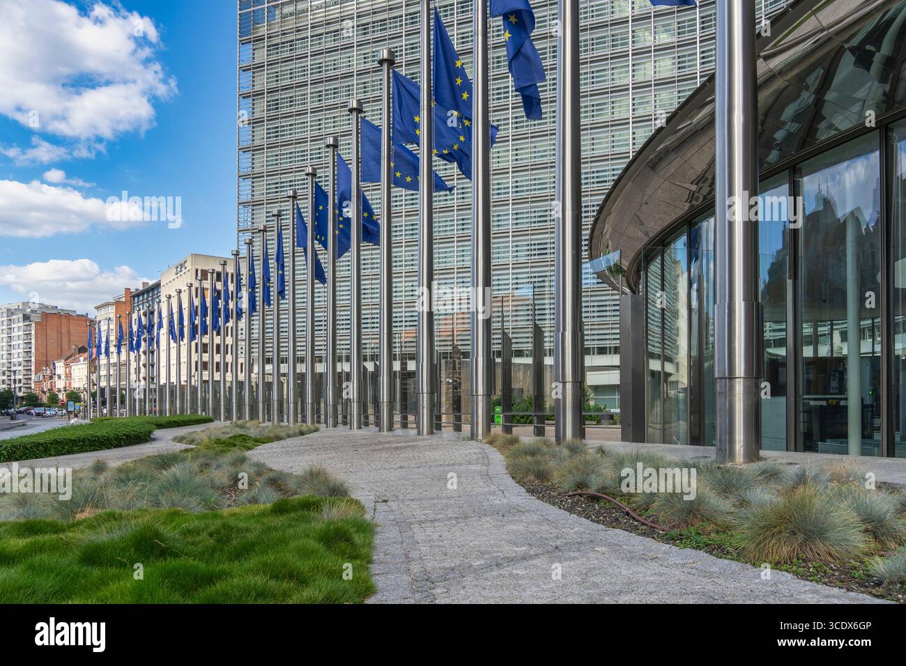 Viele EU-Flaggen vor dem berühmten Ratsgebäude in der Mitte des EU-Hauptsitzes in Brüssel spiegeln sich in der Glasfassade des Hochhauses wider Stockfoto