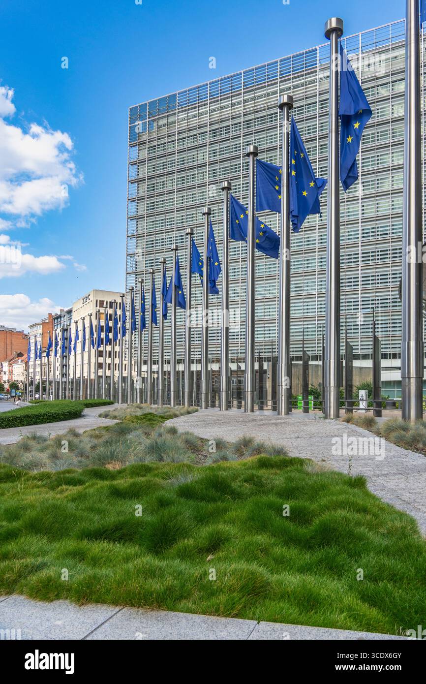 Viele EU-Flaggen vor dem berühmten Ratsgebäude in der Mitte des EU-Hauptsitzes in Brüssel spiegeln sich in der Glasfassade des Hochhauses wider Stockfoto