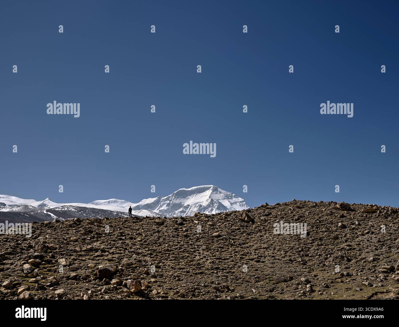 Fotograf, der auf dem Bergrücken unter dem blauen Himmel mit dem Berg cho oyu im Hintergrund steht, tibet, china Stockfoto