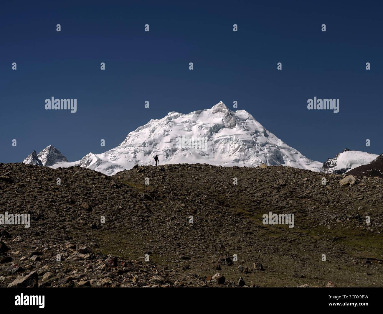 Männlicher Fotograf, der auf dem Bergrücken mit dem Berg Cholatse im Hintergrund spaziert, tibet, china Stockfoto