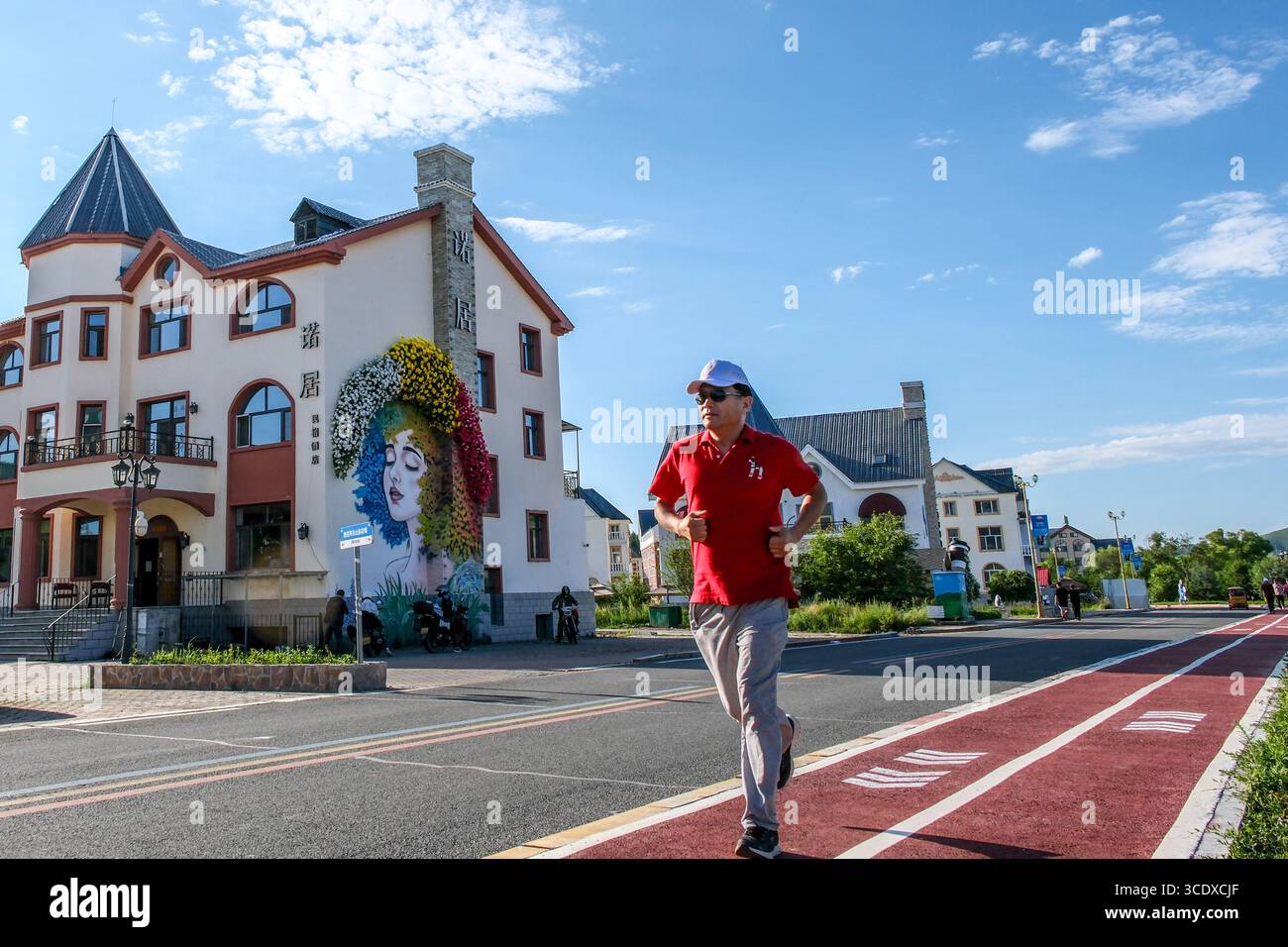 Hohhot, Chinas autonome Region Innere Mongolei. Juli 2025. Ein Mann joggt auf einer Straße in Arxan, nordchinesischer autonomer Region Innere Mongolei, 27. Juli 2025. Arxan, eine Stadt mit weniger als 40.000 Einwohnern und einer Vegetationsfläche von über 95 Prozent, liegt am südwestlichen Fuß des Dahinggan-Gebirges, dem Schnittpunkt von vier großen Graslandschaften in Nordchina. Heute ist es ein immer beliebter werdendes Reiseziel. Quelle: Ma Jinrui/Xinhua/Alamy Live News Stockfoto