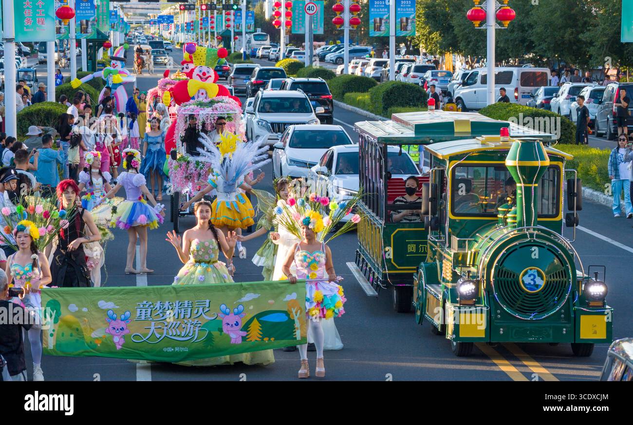 Hohhot. Juli 2025. Ein Drohnenfoto vom 27. Juli 2025 zeigt eine Floßparade auf einer Straße mit einem Sightseeing-Fahrzeug in Arxan, der autonomen Region der Inneren Mongolei im Norden Chinas. Arxan, eine Stadt mit weniger als 40.000 Einwohnern und einer Vegetationsfläche von über 95 Prozent, liegt am südwestlichen Fuß des Dahinggan-Gebirges, dem Schnittpunkt von vier großen Graslandschaften in Nordchina. Heute ist es ein immer beliebter werdendes Reiseziel. Quelle: Ma Jinrui/Xinhua/Alamy Live News Stockfoto