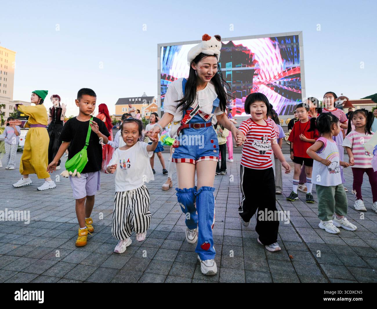 Hohhot, Chinas autonome Region Innere Mongolei. Juli 2025. Kinder interagieren mit einem Darsteller während einer Flottenparade auf einem Platz in Arxan, Nordchinas autonomer Region Innere Mongolei, 27. Juli 2025. Arxan, eine Stadt mit weniger als 40.000 Einwohnern und einer Vegetationsfläche von über 95 Prozent, liegt am südwestlichen Fuß des Dahinggan-Gebirges, dem Schnittpunkt von vier großen Graslandschaften in Nordchina. Heute ist es ein immer beliebter werdendes Reiseziel. Quelle: Ma Jinrui/Xinhua/Alamy Live News Stockfoto