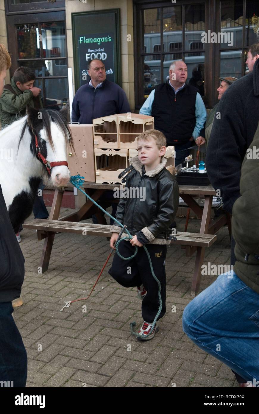 Piebald Pony zum Verkauf, wird von einem jungen Zigeuner gehalten. Battersea, London. London Cob Horse Dealer „Back End Day“-Verkauf außerhalb des Flanagans Arms Pub. Es ist der letzte Handelstag im Jahr 7. November 2010. Männer, Händler, die sich unterhalten, auf dem Tisch sind dekorative Vogelkäfige aus Holz, die verkauft werden sollen. Battersea, South London, England 2010er Jahre, UK HOMER SYKES. Stockfoto