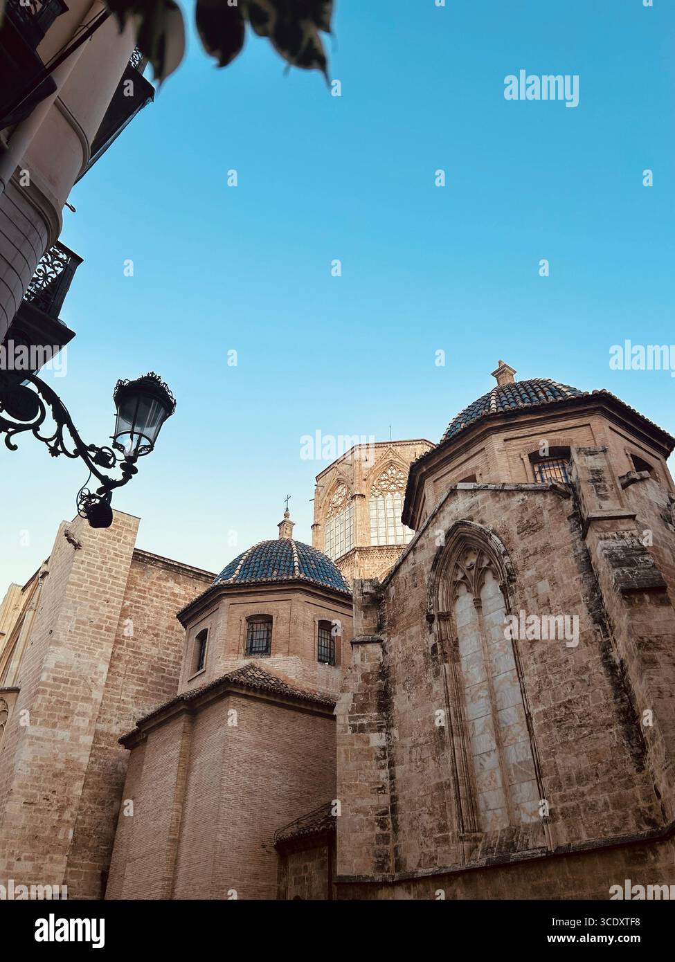 Historische Architektur der valencianischen Kathedrale unter einem klaren blauen Himmel. Mittelalterliche Kuppel, Steinmauern, ikonisches spanisches Erbe - Smartphone-aufgenommenes Stockfoto