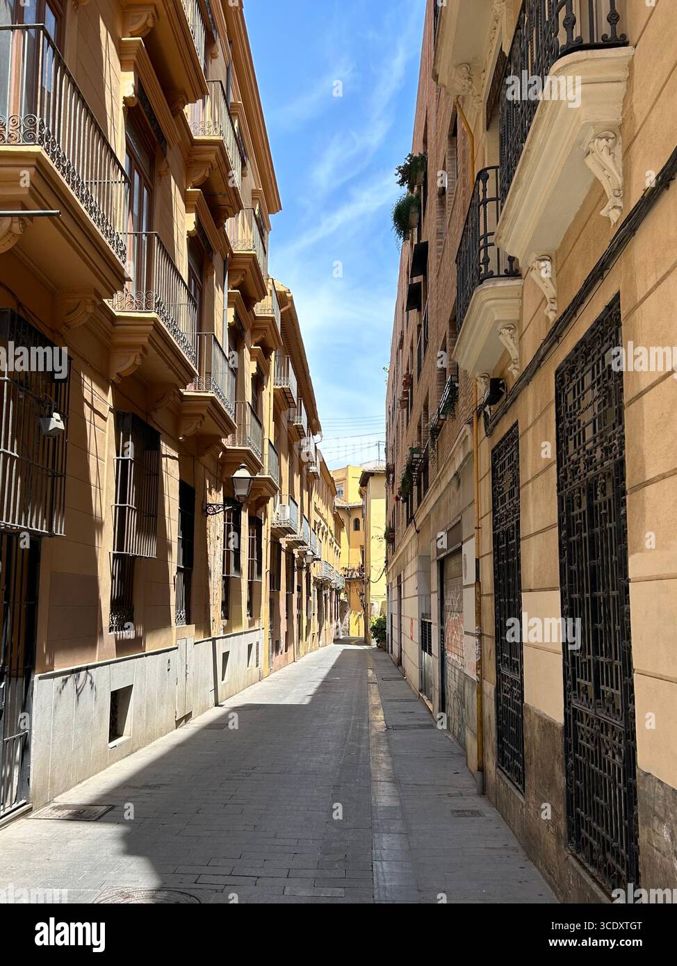 Enge Fußgängerzone im Viertel El Carme, Valencia, Spanien, mit Wohnhäusern im mediterranen Stil und Balkonen an einem sonnigen Tag - Smartphone-aufgenommenes Stockfoto