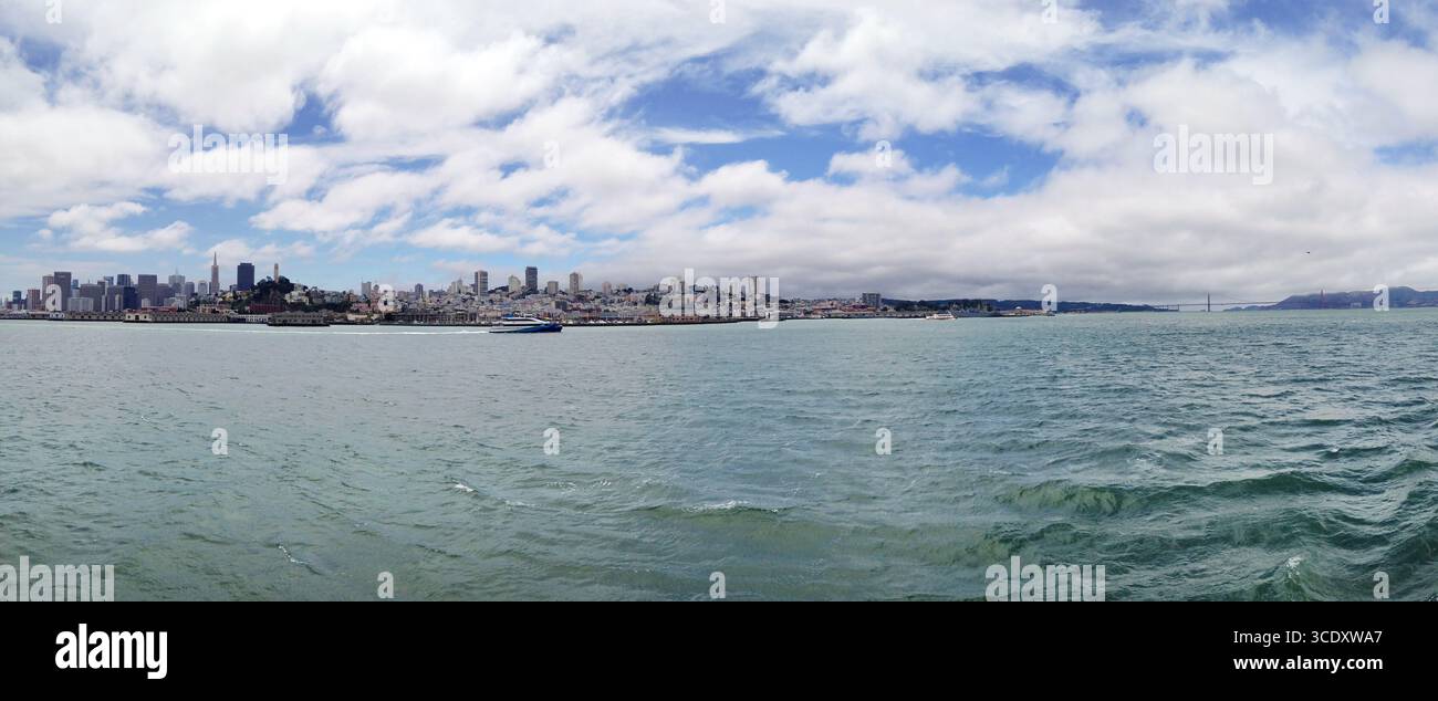Weites Panorama, das die Skyline der Stadt mit einer weitläufigen Uferpromenade und bewölktem Himmel erfasst. Ideal für Hintergründe oder Designs. Stockfoto