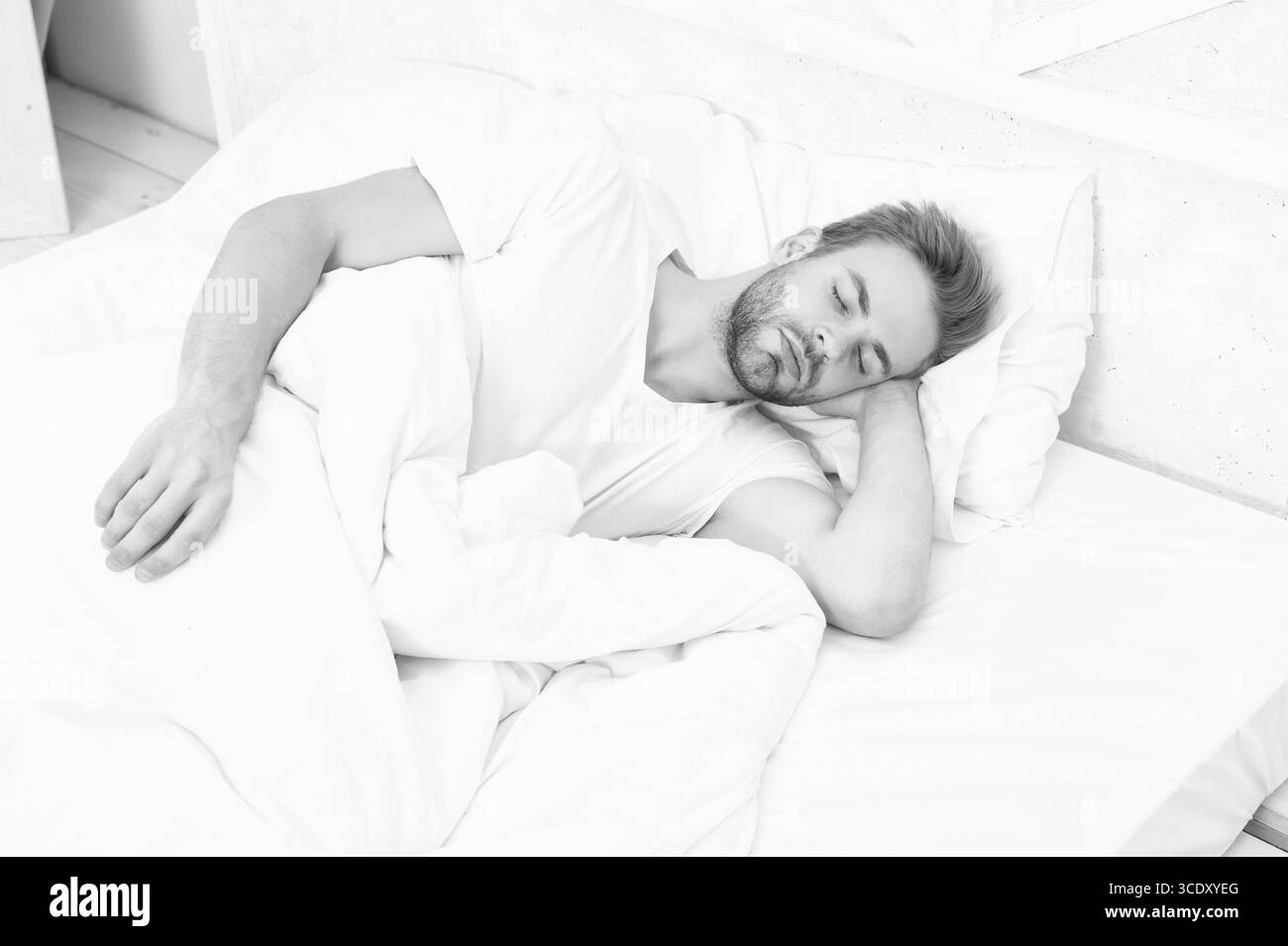 Schlafender junger Mann, der schläft. Erholsame Ruhe in einem komfortablen Bett. Mit geschlossenen Augen liegen. Tiefer Männerschlaf. Mann, der nachts schläft. Schläfriger Mann, der auf ihm liegt Stockfoto