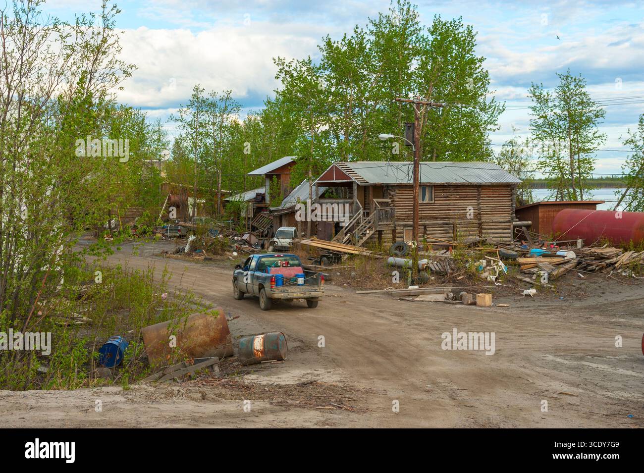 Ein alter blauer Pickup-Truck, der an einem Blockhaus am Ufer des Yukon River vorbeifuhr, nachdem der Eisstau im Frühjahr 2013 in Galena, Alaska, Überschwemmungen verursacht hatte Stockfoto