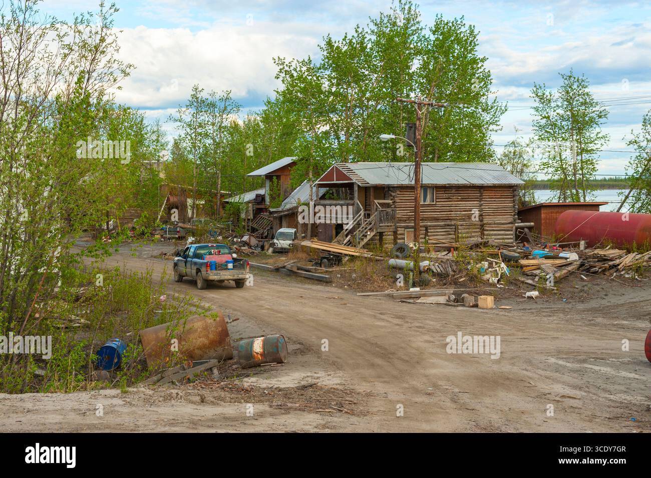 Ein alter blauer Pickup-Truck, der an einem Blockhaus am Ufer des Yukon River vorbeifuhr, nachdem der Eisstau im Frühjahr 2013 in Galena, Alaska, Überschwemmungen verursacht hatte Stockfoto