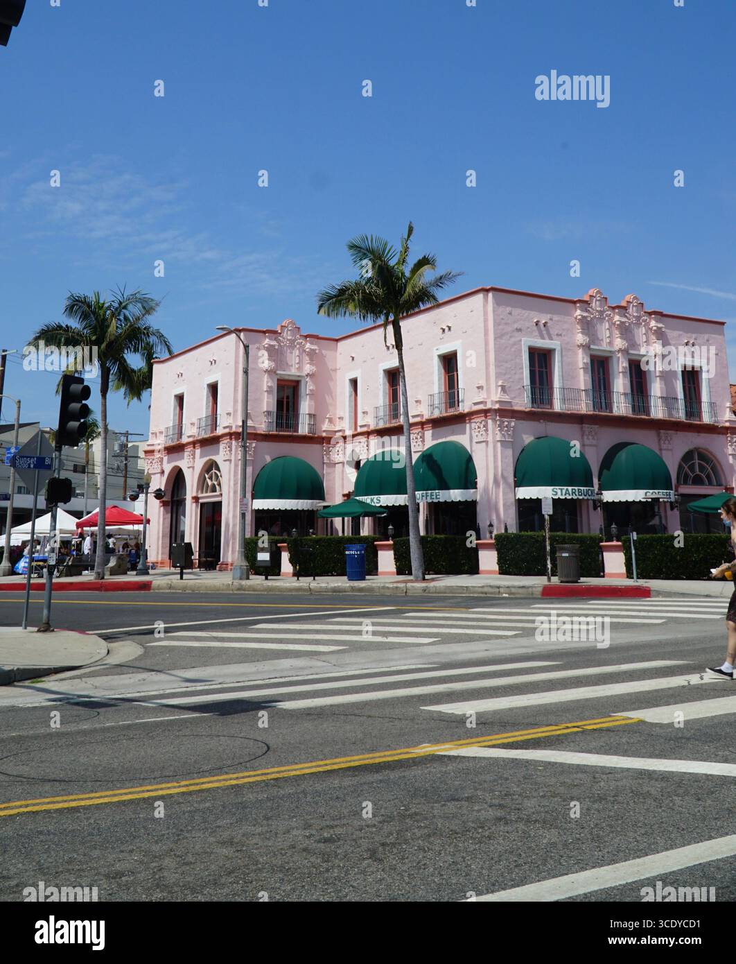 Elegantes Gebäude im spanischen Kolonialstil in sanftem Rosa mit grünen Markisen, gelegen am Sunset Boulevard in Beverly Hills, Kalifornien Stockfoto