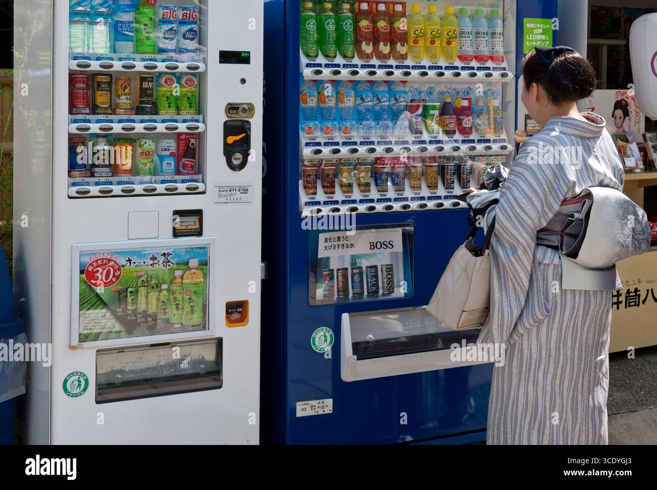 Frau, die einen traditionellen japanischen Kimono trägt, kauft ein Getränk aus einem modernen Getränkeautomaten für einen Kontrast von Neu und Alt in Kyoto, Japan. Stockfoto