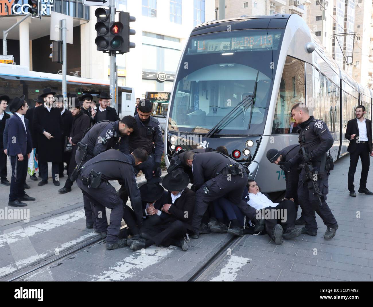 Ultraorthodoxe Juden, die gegen einen IDF-Entwurf protestieren und die Straße blockieren, werden am 25. Februar 2025 von der Polizei in Jerusalem auf den Bürgersteig gezerrt. Stockfoto