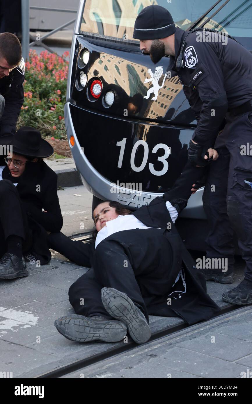 Ultraorthodoxe Juden, die gegen einen IDF-Entwurf protestieren und die Straße blockieren, werden am 25. Februar 2025 von der Polizei in Jerusalem auf den Bürgersteig gezerrt. Stockfoto