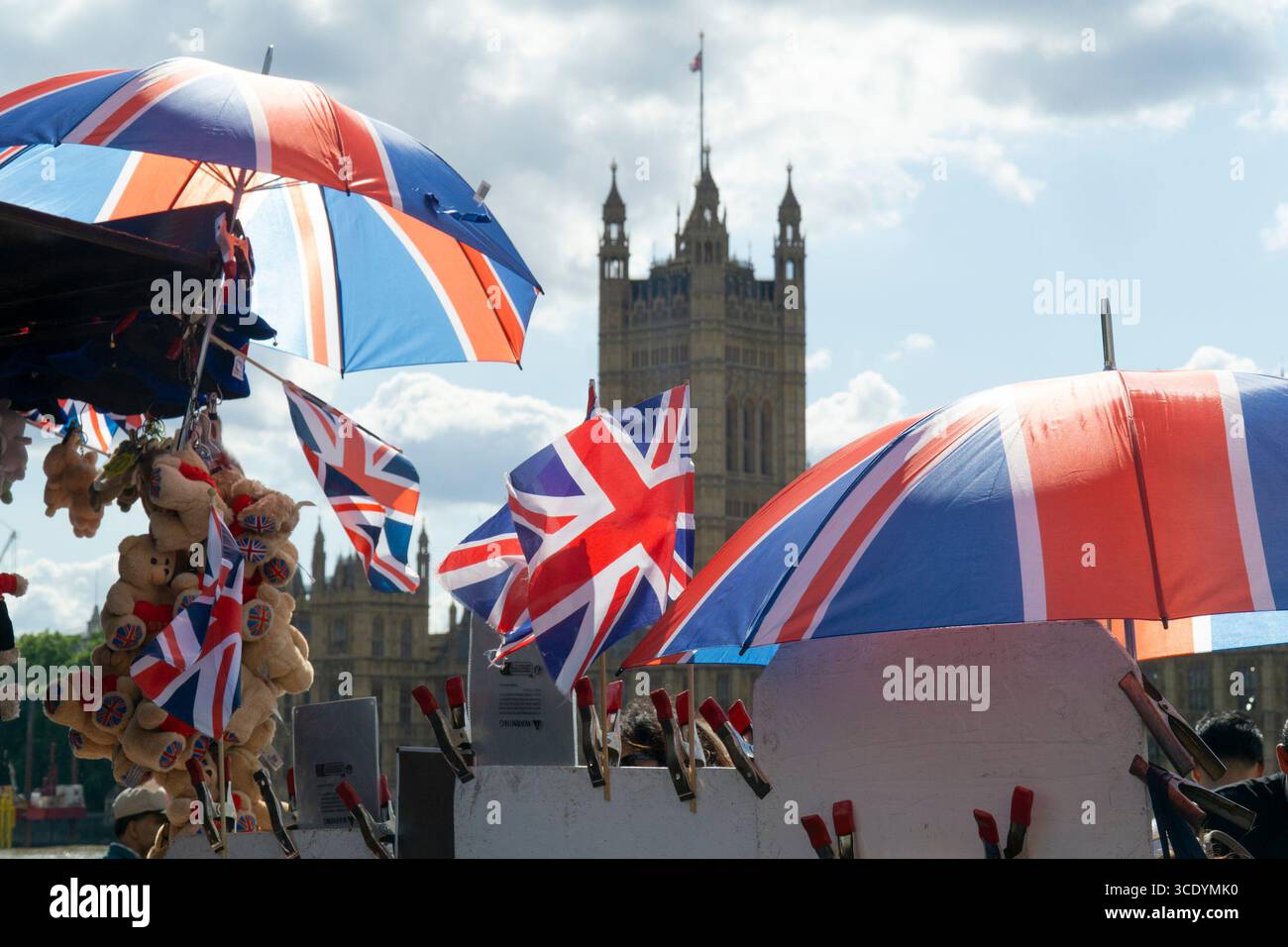 Großbritannien Wetter, 14. August 2025: Als die Temperaturen im Zentrum Londons wieder 27 Grad erreichten, verkauft ein Souvenirstand an der Westminster Bridge union Jack Flags, Regenschirme und Teddybären, mit dem Elizabeth Tower of the Houses of Parliament (der Big Ben beherbergt). Quelle: Anna Watson/Alamy Live News Stockfoto