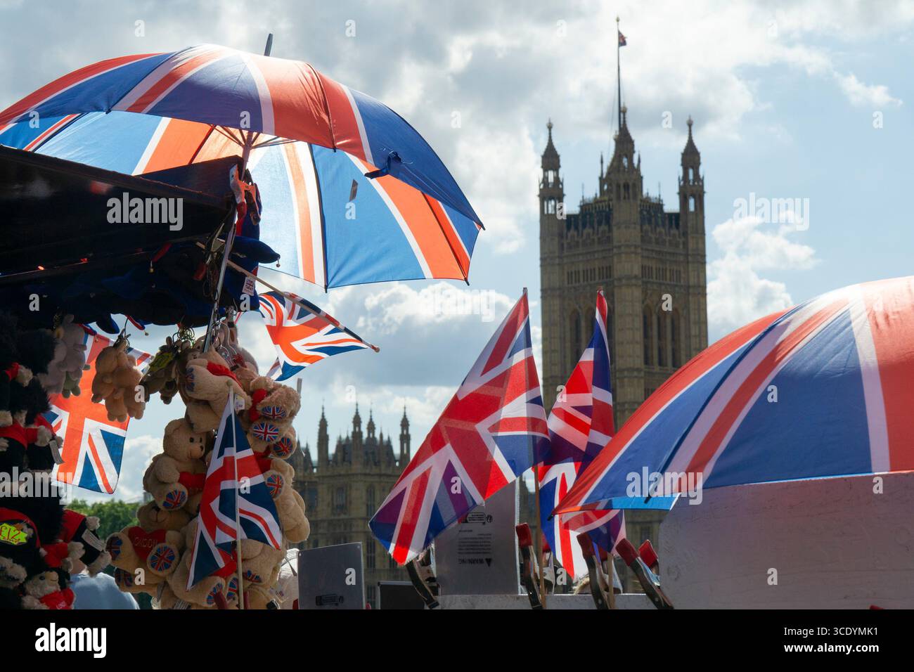Großbritannien Wetter, 14. August 2025: Als die Temperaturen im Zentrum Londons wieder 27 Grad erreichten, verkauft ein Souvenirstand an der Westminster Bridge union Jack Flags, Regenschirme und Teddybären, mit dem Elizabeth Tower of the Houses of Parliament (der Big Ben beherbergt). Quelle: Anna Watson/Alamy Live News Stockfoto
