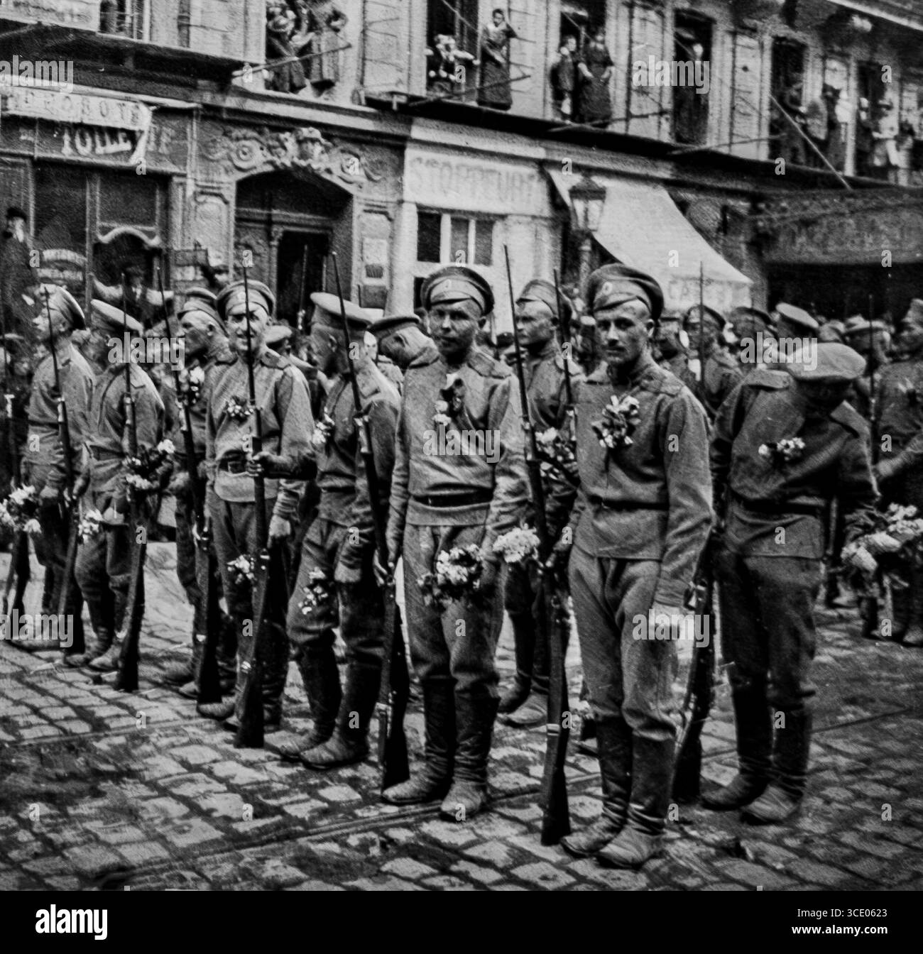 Foto aus L’Illustration, 29. April 1916, mit Soldaten der russischen Regimenter General Lohvitskis während eines Stopps bei der triumphalen Parade am 21. April in Marseille. Die Männer tragen russische Uniformen mit Blumenschmuck, tragen Gewehre und stehen auf einer kopfsteingepflasterten Straße. Dieser Moment symbolisiert die Einheit der Alliierten und die feierliche Begrüßung des Beitrags Russlands zur Westfront im Ersten Weltkrieg Stockfoto