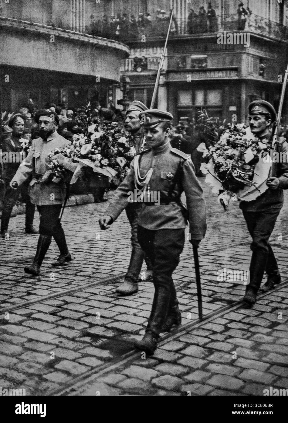 Foto aus L’Illustration, 29. April 1916, zeigt die ersten russischen Soldaten, die während des Ersten Weltkriegs in Frankreich ankamen. Die Parade in Marseille zeigt einen französischen Alpensoldaten an der Spitze der Kolonne, gefolgt von russischen Soldaten, die Sträuße in alliierten Farben tragen. Diese feierliche Begrüßung spiegelt die französisch-russische Allianz und die Solidarität zwischen den Alliierten während des Ersten Weltkriegs wider, gefangen unter jubelnden Menschenmassen und Kopfsteinpflasterstraßen. Stockfoto