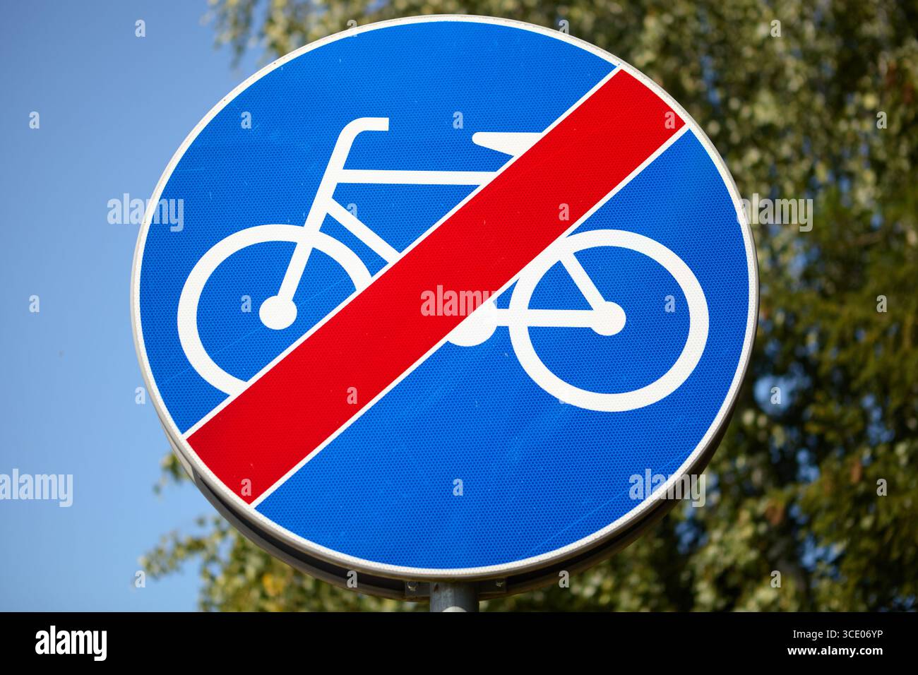 Kreisförmiges blaues Verkehrszeichen mit einer roten Diagonallinie über einem Fahrradsymbol, das das Ende eines bestimmten Radweges oder einer bestimmten Radroute angibt. Wird zur Information von cy verwendet Stockfoto