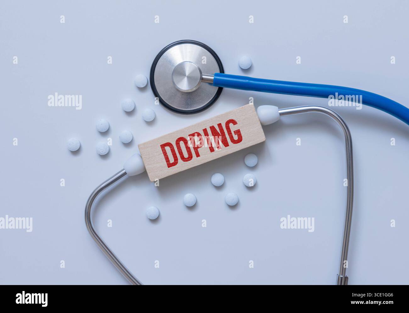 Auf blauem Hintergrund ein Stethoskop, eine medizinische Maske, Pillen, ein Stift und eine weiße Karte mit dem Text DOPING. Blick von oben. Stockfoto