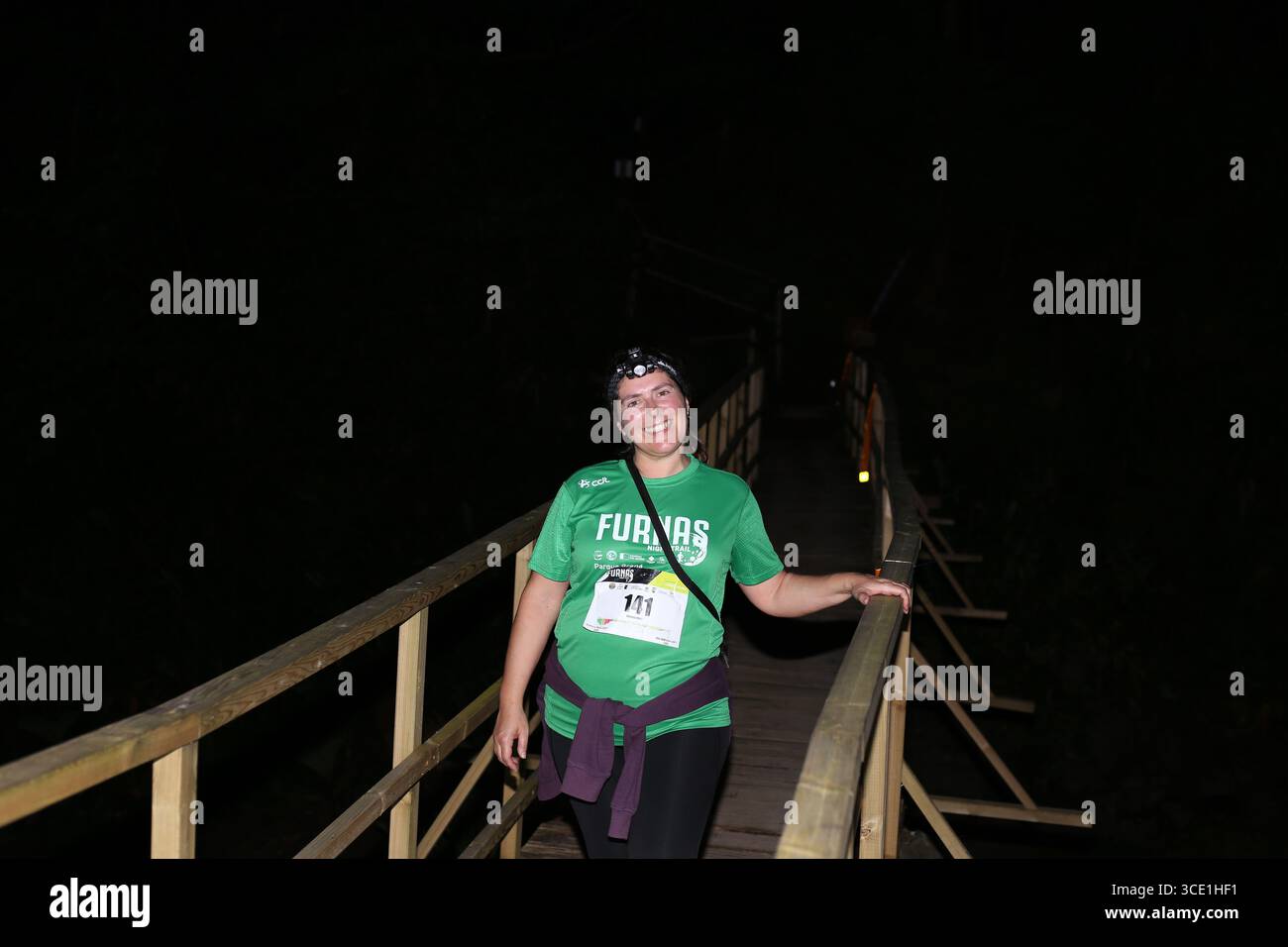Teilnehmer auf der beleuchteten Brücke während des Furnas Night Trail Events auf den Azoren Stockfoto